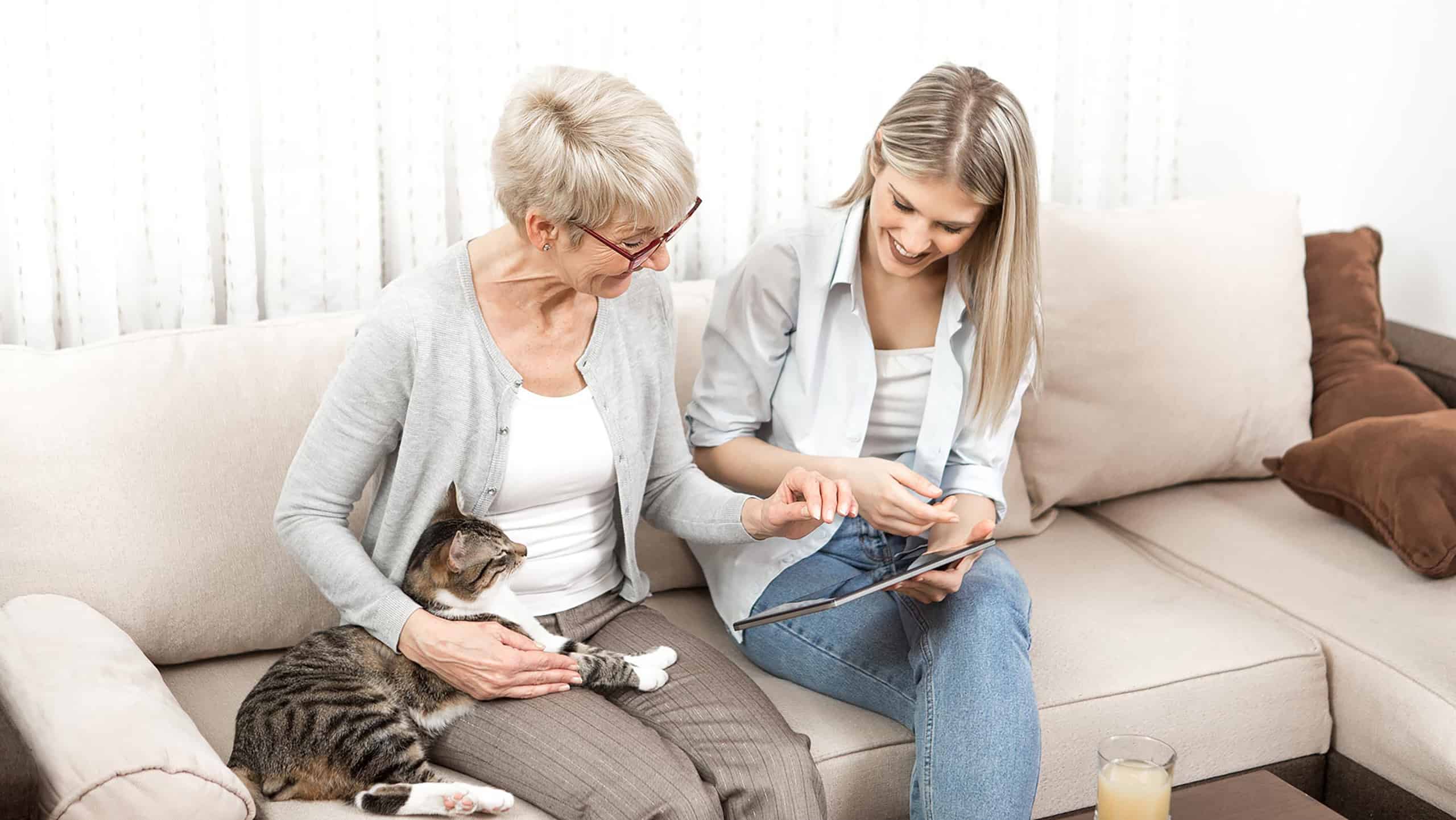 Mother and daughter sitting on sofa using a laptop on